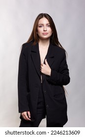 Woman in a black jacket. Female with long brown hair posing on gray background. - Shutterstock ID 2246213609