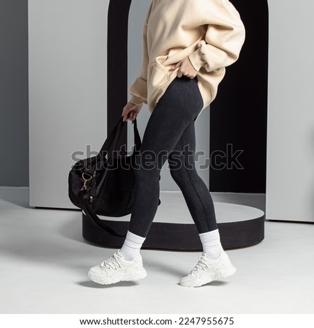 Woman in black leggings and white sneakers. Vertical. Casual sports style. Slimming leggins