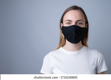 Woman In A Black Medical Mask, Isolated On A Gray Background