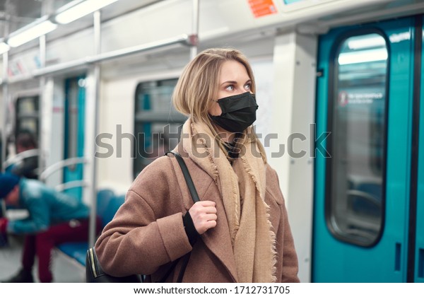 Woman in black medical mask standing in subway\
near carriage. Coronavirus\
epidemic.