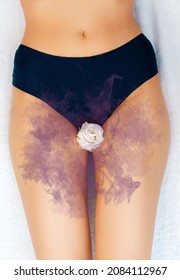 A woman in black panties with a white rose in the intimate area. A lilac cloud symbolizing an unpleasant smell. Close-up. Vertical. The concept of gynecology and female's diseases.