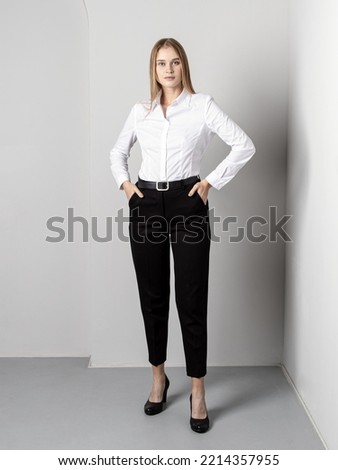 Woman in black pants and white shirt. Classic trousers. In full growth