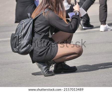 Woman in black pantyhose and miniskirt takes the photos in the square

