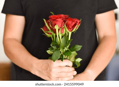 Woman in black shirt holding bouquet of red roses. 