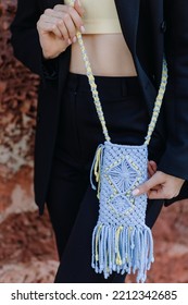 A Woman In A Black Suit Holds A Knitted Phone Case In Ukrainian Colors With Macrame On The Street. Close Up. High Quality Photo