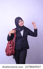 A woman in a black suit and black jacket is holding a red bag and smiling. - Shutterstock ID 2278069037