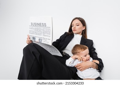 Woman In Black Suit Reading Business Newspaper Near Happy Son On White