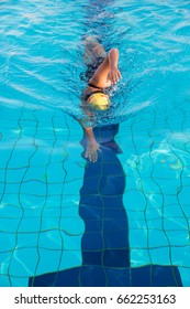 A Woman In Black Swim Suits And Yellow Cap Is Swimming In Freestyle Stroke (front Crawl) In A Swimming Pool With Clear And Blue Water.