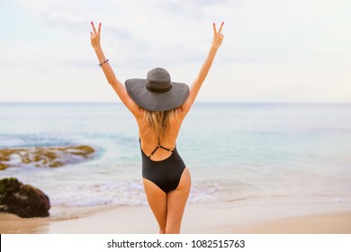 Woman In Black Swimsuit And Summer Hat On The Beach