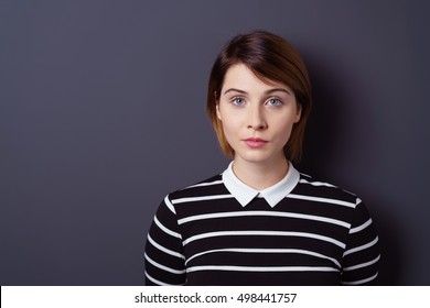 Woman in black and white striped shirt with serious facial expression over dark background with copy space