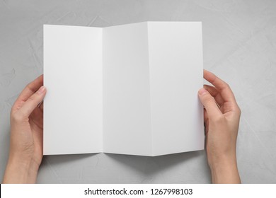 Woman with blank brochure on light background, above view. Mock up for design