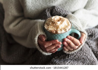 Woman With Blanket Warming Her Hands In Mug Of Hot Drink With Whipped Cream