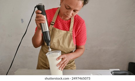 Woman blending ingredients in kitchen with immersion blender - Powered by Shutterstock