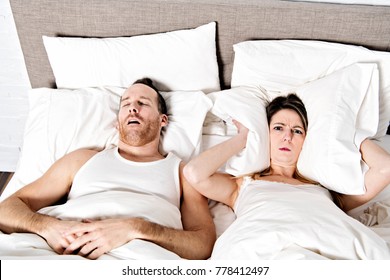 A Woman Blocking Ears While Man Snoring On Bed