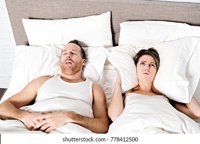 A Woman Blocking Ears While Man Snoring On Bed