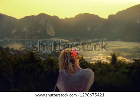 A woman with blond hair with a flower on her ear was appreciating the view of the sea and mountains in Phi Phi island Thailand