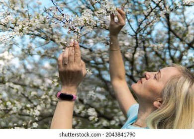 woman with blonde hair hold a branch with blooming flowers early spring