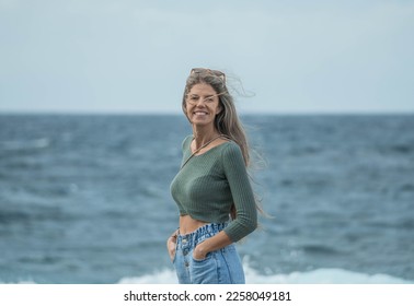 Woman with blonde hair looking at the camera near the sea  - Shutterstock ID 2258049181