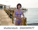 Woman in blue bikini relaxing in Turkish resort while basking on the beach.