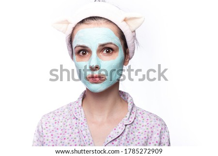 woman with blue clay face mask, funny eared hair band, home face skin care