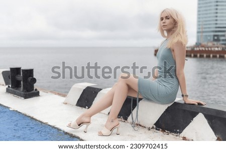 Woman in blue dress enjoys sea on the pier.