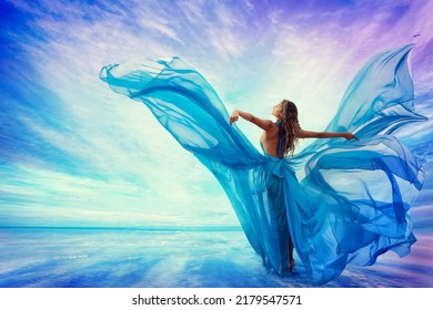 Woman in Blue Dress Flying on Wind looking at Sky and Sea. Beautiful Model Arms outstretched enjoying Freedom at Beach Summer Resort Rear view. Artistic Women Silhouette in Fantasy Gown as Butterfly - Shutterstock ID 2179547571