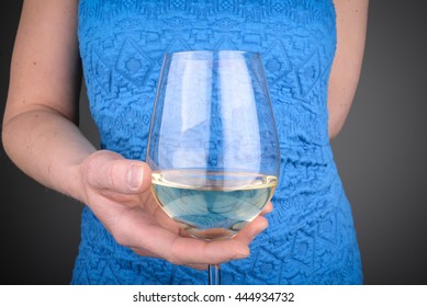 Woman in a blue dress holding a glass of white wine. Being pregnant, no alcohol concept. 