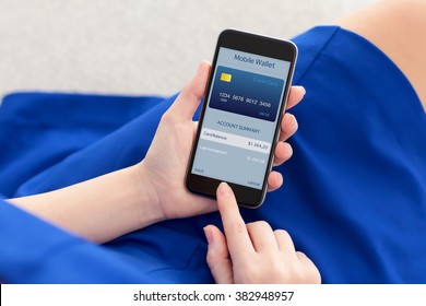 woman in a blue dress holding a phone with app mobile wallet on the screen