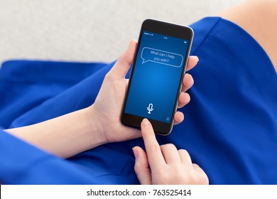 woman in blue dress holding phone with app personal assistant on screen