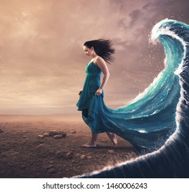 A woman with a blue dress and large wave behind her. 