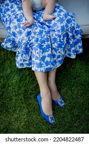 Woman In Blue Dress And Shoes Holding Little Baby Outdoors. Parenthood Concept