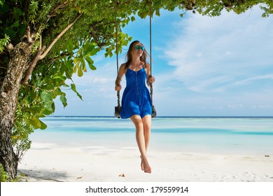 Woman In Blue Dress Swinging At Tropical Beach