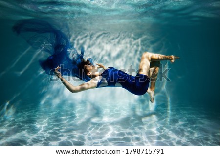  Woman in blue dress under water.