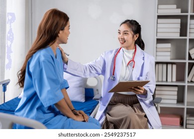 A woman in a blue hospital gown is sitting in a hospital bed while a doctor talks to her - Powered by Shutterstock