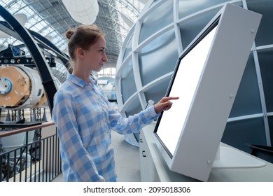 Woman In Blue Plaid Shirt Touching Blank Interactive Touchscreen White Display Of Electronic Kiosk At Futuristic Exhibition Or Museum. White Screen, Mock Up, Copyspace, Template, Technology Concept.