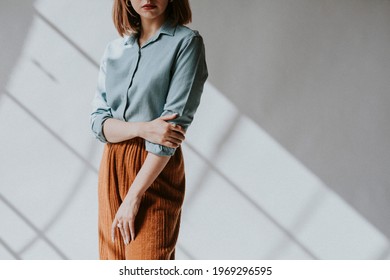 Woman In A Blue Shirt By The White Wall