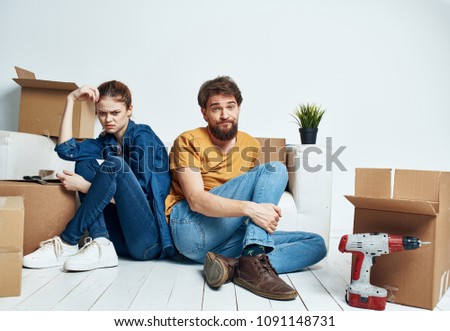 A woman in a blue suit and a man in a T-shirt are sitting on the floor                              