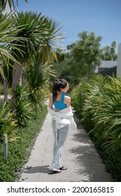 Woman In Blue Top And Jeans Walking In Tropical Resort Hotel.