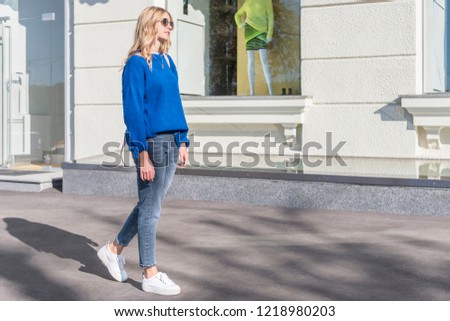 woman in blue walking in the city at the shop window