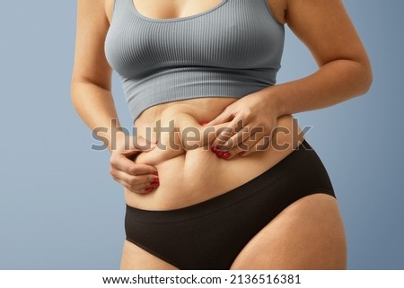 Woman body fat belly. Obese woman hands holding excessive tummy fat. Change diet lifestyle concept to shape up healthy stomach muscle. Studio anonymous shot photo of body parts. Imagine de stoc © 
