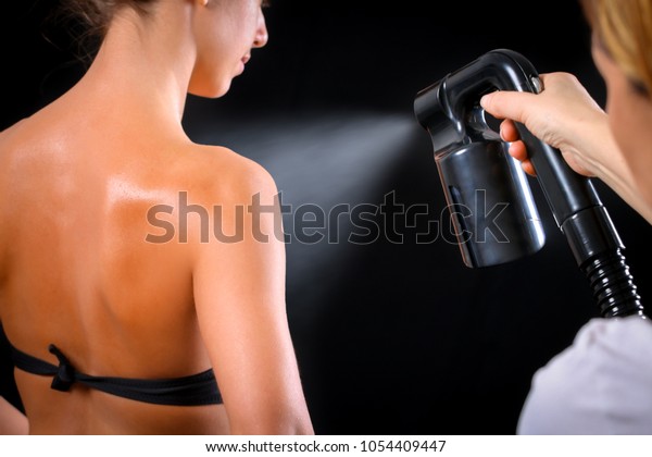 Woman body paint with airbrush in professional\
beauty salon