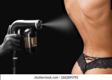 Woman Body Paint Instant Tan Spray Skintone With Airbrush In Professional Beauty Salon On Black Background.