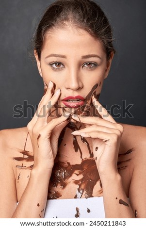 Woman, body paint and portrait in studio for chocolate, temptation and sweet craving for messy and unique. Young person with guilty facial expression and isolated for candy, brown sauce and sugar