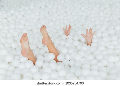 woman body parts stick out white plastic balls in the dry pool. Copy splace. Adult childhood at Playground with pit-ball. She swung to throw the ball.