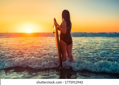 Woman with bodyboard catching breaking waves at sunset, Moana Beach, South Australia