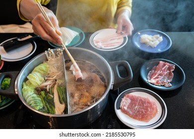 Woman Boiling Meat In Hotpot. Hotpot Is An Interactive Meal In Which Diners Sit Around A Simmering Pot Of Soup At The Center Of The Table With Ingredients.