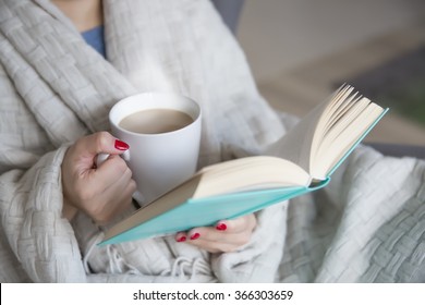 woman with a book and cup of hot drink