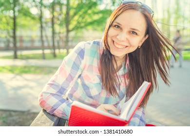 Woman with a book in his hands in the Park. Female, student is reading an interesting book sitting on the bench in the park