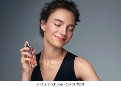 Frau mit einer Flasche Parfum. Foto von Frau mit perfektem Make-up auf grauem Hintergrund. Schönheitskonzept