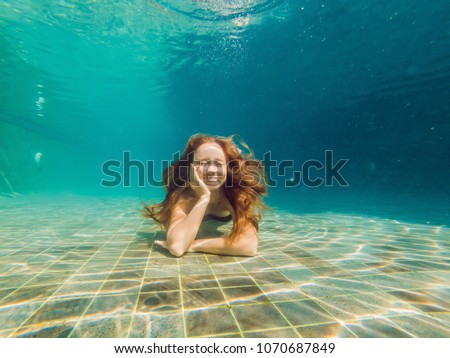 Woman at the bottom of the pool, she dives under the water
